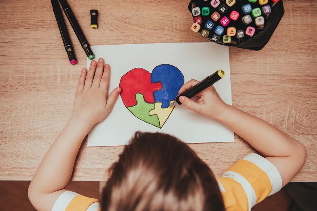 dziecko koloruje narysowane na kartce serce